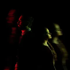 An experimental portrait using slow shutter speed to create a motion blur effect. The red light adds a touch of drama and passion.