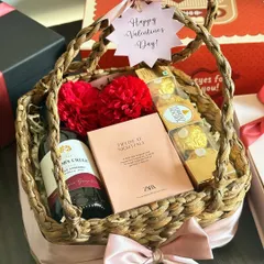 Our "Basket of Love" is the perfect Valentine's Day gesture. This wicker basket is filled with red wine, a Zara perfume, a face sheet mask, and Ferrero Rocher, all tied with a pink ribbon.