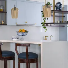 Lighting is everything. In this kitchen, we used beautiful glass pendant lights to illuminate the breakfast bar, adding a touch of warmth and artistry to a highly functional space. The blue and white porcelain adds a classic touch.