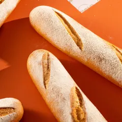 Freshly baked baguettes with a dusting of flour. The strong directional light emphasizes their perfect shape and scoring.
