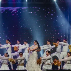 A bride's performance with her squad, using golden pom-poms to add a pop of shimmer and energy. Simple props can elevate a performance and make it more visually engaging.