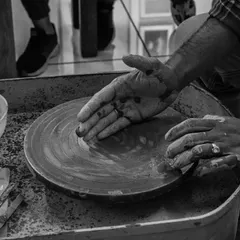 A black and white photo capturing the moment of centering clay on the wheel. This is where the connection between the artist and the material begins.