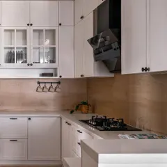 This all-white kitchen is clean, bright, and timeless. We used a wood-look backsplash to add warmth and texture, and included a mix of open and closed storage for both display and practicality.