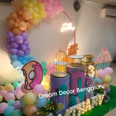 A fun and colorful candy and donut-themed party. The pastel balloon arch and giant donut and cupcake props create a sweet and playful atmosphere.