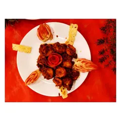 My Chilly Prawns are simply the best. This top-down shot shows the beautiful presentation with a tomato rose, highlighting the rich, glossy sauce and perfectly cooked prawns.