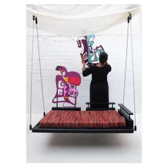 Here you can see the modularity in action. The artist is placing one of the sculptural backrests onto the swing's base, demonstrating how easily the piece can be customized to suit your mood or seating preference.