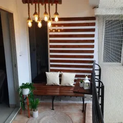 This urban balcony design is clean, classy, and comfortable. I used polished pinewood for the wall panelling and a custom bench, complemented by a beautiful rope and bamboo hanging lamp that adds a rustic yet modern touch.