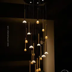 This multi-pendant chandelier combines textured glass and polished brass rods to create a stunning visual effect. It is ideal for stairwells or rooms with high ceilings, where its staggered design can be fully appreciated.