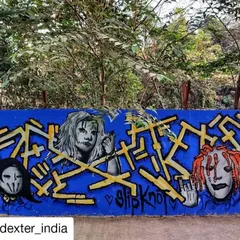 A tribute to the metal band Slipknot, featuring their iconic masks alongside complex yellow lettering on a bright blue wall. A great example of subculture representation in street art.