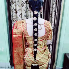 A traditional long braid for bride Jaylakshmi's Varapooja ceremony. This hairstyle features classic round, coin-style hair ornaments placed neatly along the length of the braid.