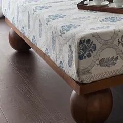 A close-up of a custom-made bed in the West Coast Residence. The spherical wooden legs are a playful and unexpected detail that elevates a simple piece of furniture.