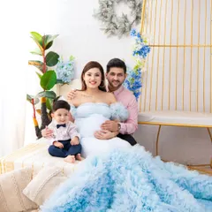 A family portrait filled with love and excitement. The mother's flowing blue gown is the centerpiece of this shot, perfectly complementing the family's coordinated attire.