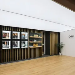 The entrance to the Oriflame office, designed around the concept of 'HOME.' A unique slanted fabric ceiling mimics the cozy feel of a hut, while the product display wall uses clean lines and wood battens.