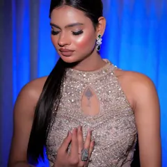 A serene portrait with the model looking down, highlighting the sleek ponytail and modern jewelry.