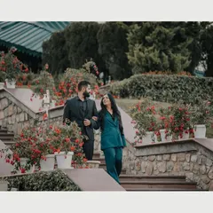 A couple shares a walk down a flower-lined staircase in the hills. This candid shot captures the elegance and romance of a pre-wedding session in a picturesque mountain resort.