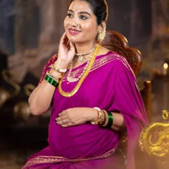 This portrait from a maternity shoot showcases a traditional look. The makeup is subtle, with warm tones that complement her magenta saree and gold jewelry.