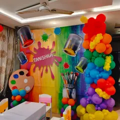 A colorful and creative art party theme for Tanishka. The backdrop is a rainbow of colors, decorated with paint splatters, brushes, and a palette, all brought together with a vibrant balloon pillar.