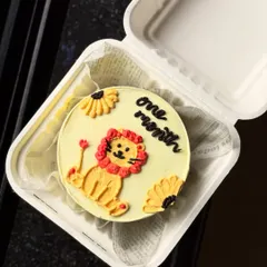 An adorable bento cake to celebrate a one-month milestone. This design features a cute, hand-piped lion cub on a soft yellow background, perfect for celebrating a new baby.