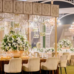 An elegant outdoor dinner setup with velvet chairs, mirrored tables, and hanging crystal chandeliers. This creates a sophisticated and glamorous dining experience under the stars.