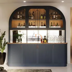 This bespoke home bar unit is designed to be a stunning focal point. It features a dark matte finish with an arched, backlit display cabinet, fluted lower shutters, and a warm wooden countertop, seamlessly integrating into a modern living space for elegant entertaining.