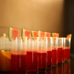 A row of refreshing watermelon juice, garnished with fresh slices. We offer a variety of fresh juices and mocktails to complement our food and keep your guests hydrated in style.