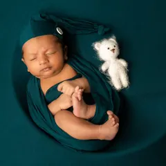 A classic moon prop setup. This portrait showcases a secure wrap in a rich teal color, with a tiny teddy bear prop to add a touch of sweetness.