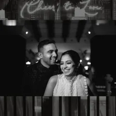 Laughter under a 'Cheers to Love' sign at a Sangeet night in Goa. This black and white shot freezes a genuine, candid moment, showing the fun and energy of wedding celebrations.