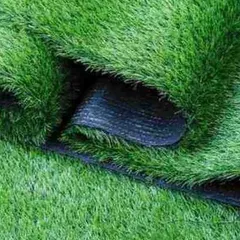 A close-up view of the turf's edge reveals the thick, multi-layered backing and dense stitching. This robust construction is key to the product's durability and its ability to withstand heavy foot traffic and the elements.