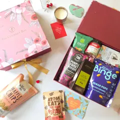 A flat lay of one of my Valentine's Day hampers, showing the variety of gourmet snacks included. From waffle chips and pretzels to jowar pops and purple sweet potato chips, it's a feast for the senses.