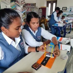 Two students work together to build a model of an automated street light system, learning about basic circuits and power sources.