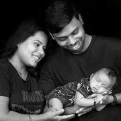 A classic black and white family portrait. This timeless style removes distractions and focuses purely on the emotion and connection between new parents and their baby.