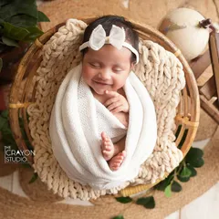 A top-down view of a swaddled newborn, revealing a sweet, sleepy smile. This angle emphasizes how tiny and perfect they are, capturing the curled toes and peaceful expression.