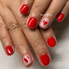 Simple, cute, and perfect for short nails. This classic red manicure is elevated with two accent nails featuring a sheer pink base and a single red heart.
