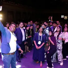 An attendee takes a selfie with a group on stage, showing the celebratory and social side of the UXINDIA conference.