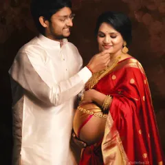Celebrating motherhood with traditional elegance, this couple's portrait is rich in cultural beauty. The vibrant red saree, gold jewelry, and the gentle interaction make this a warm and intimate traditional maternity photograph.