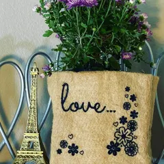 Sometimes, the simplest message is the most powerful. This jute grow bag, embroidered with the word 'love' and a floral design, turns a simple flowering plant into a heartfelt gift for someone special.