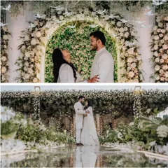 The happy couple framed by the magnificent floral arch. This shot shows how the grand scale of the white rose and greenery backdrop creates an intimate yet spectacular setting for their engagement photos.
