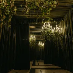 A grand gateway draped in opulent dark fabrics and lit by cascading chandeliers. This entrance sets a dramatic and luxurious tone for an unforgettable evening celebration.