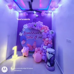 A butterfly-themed first birthday decoration for a home party. I used a round backdrop with purple and pink balloons and a light-up number '1' to fit the space perfectly.