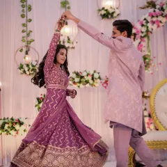 The couple shares a dance at their engagement party, the bride's purple Anarkali twirling beautifully as her partner leads her.