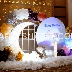 A charming photo corner with a lighted moon prop, a teddy bear sitting on fluffy clouds, and a balloon arrangement in a beautiful color scheme.