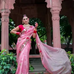 Another angle of the woman in the pink saree, showcasing the full length and beautiful drape of the fabric as it flows in the wind.