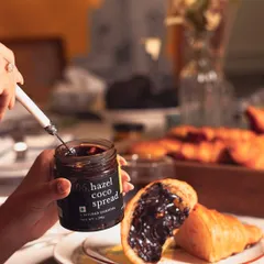 Our indulgent Hazel Coco Spread being generously slathered on a flaky croissant. Made without refined sugar, this rich chocolate and hazelnut spread is a breakfast favourite and a versatile pantry staple.