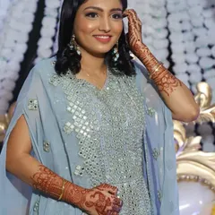 A happy client showing off her party-ready look. Her makeup is soft and glowing to complement the mirror work on her dress, and you can see the peacock and elephant motifs in her mehendi.
