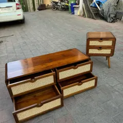 A matching set of a four-drawer chest and a two-drawer bedside table. Both pieces feature teak wood, rounded edges, and cane-fronted drawers, showcasing a cohesive design language. The open drawers reveal the quality of the craftsmanship.