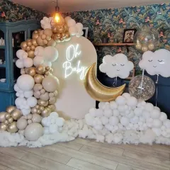 A dreamy "Oh Baby" themed decor for a cozy, intimate baby shower. The setup features a white arch backdrop with a neon sign, a crescent moon balloon, and a cloud of white balloons, complemented by a larger organic arch in gold and white.