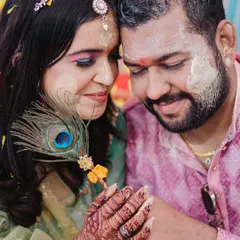 An intimate close-up of the couple during their Haldi, sharing a quiet moment amidst the fun, with a peacock feather adding a traditional touch.