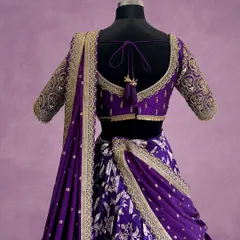 The back of this purple lehenga blouse features an elegant deep-cut design, intricate border embroidery, and beautiful tassels, ensuring you look stunning from every angle.
