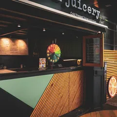 The storefront and counter of The Prezzed Juicery. The design uses a mix of wood slats, pastel green, and a bold black frame to create a fresh, modern, and inviting look.