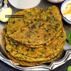 A stack of our healthy and flavorful Methi Parathas. These flatbreads are infused with fresh fenugreek leaves and spices, served with a side of butter and yogurt.